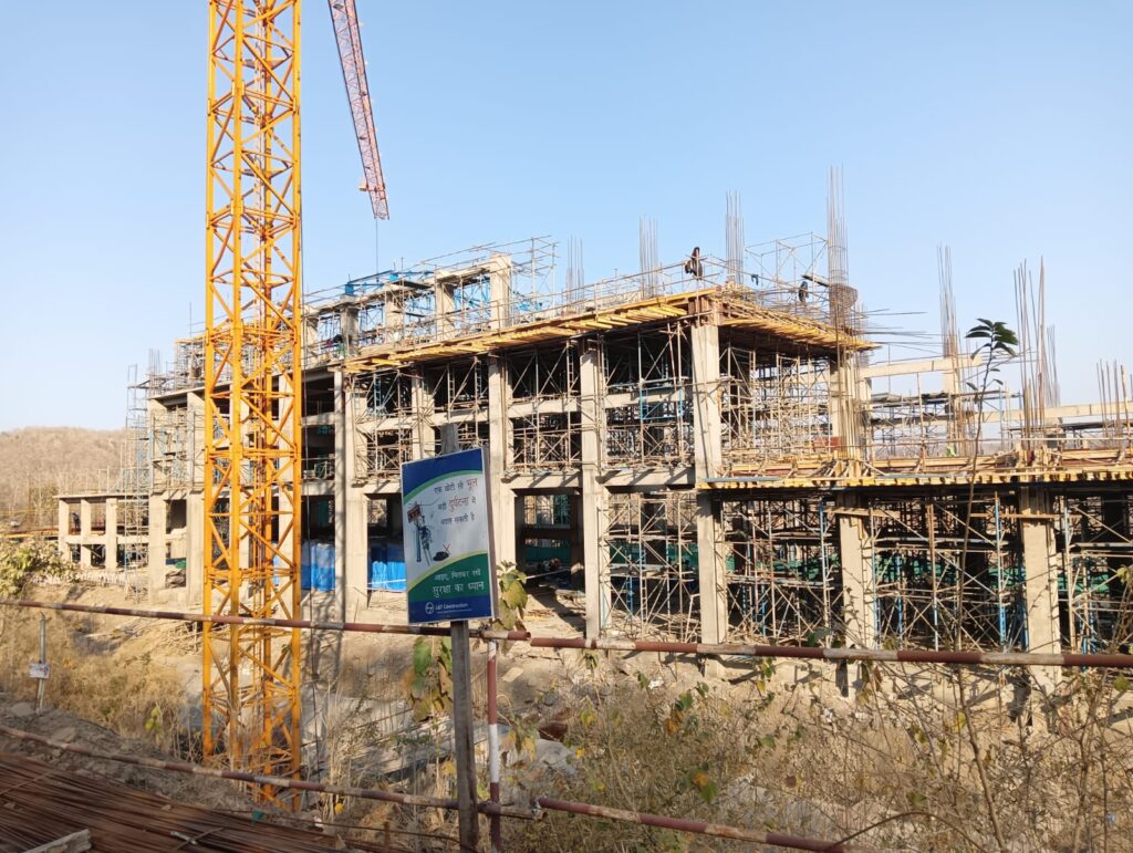 Mid-construction site view with cranes, scaffolding, and mainframe structures.